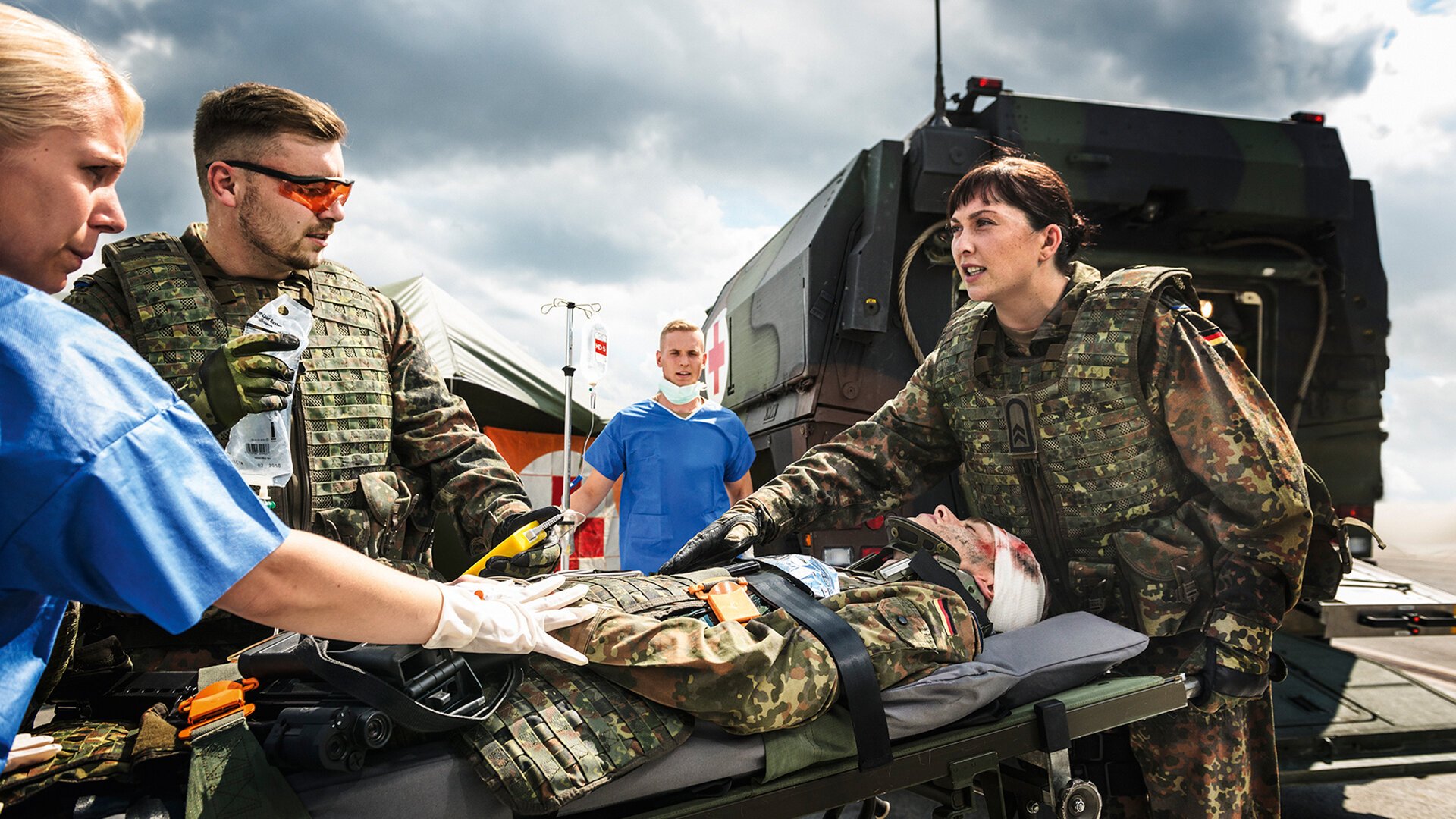 Sanitäterin und Sanitäter versorgen einen Soldaten auf einer Trage