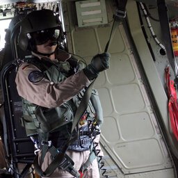 Bordtechniker in Uniform steht gesichert an einer Leine in einem Flugzeug