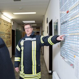 Feuerwehrmann zeigt auf einen Einsatzplan und bespricht sich mit einem Kollegen