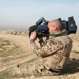 Soldat mit Kamera- und Videoausrüstung filmt in der Wüste
