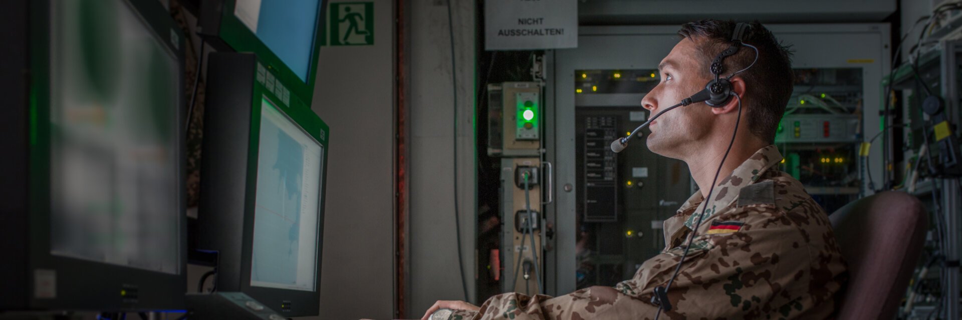 Bundeswehrsoldat mit Headset arbeitet vor einem Monitor
